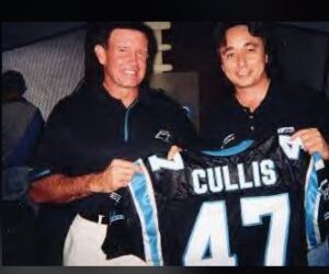 2 white males holding a football jersey